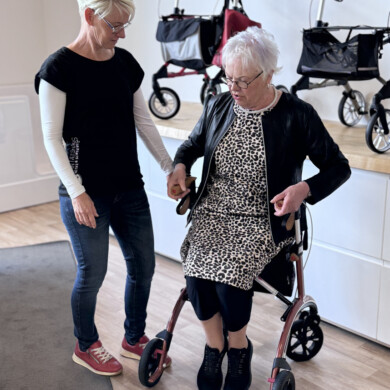 Seniorin im Rollstuhl mit Betreuerin in Pflegeeinrichtung.